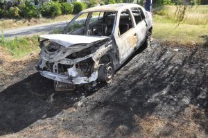 Renault Thalia doszczętnie spalony, stojący na wypalonej trawie na podjeździe do posesji